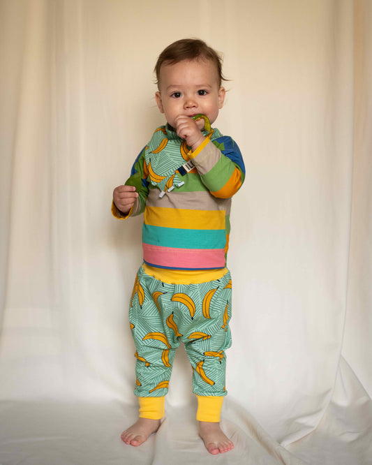 child wearing Bandana bib taggy dribble on mint colour organic cotton jersey with bananas print and trousers