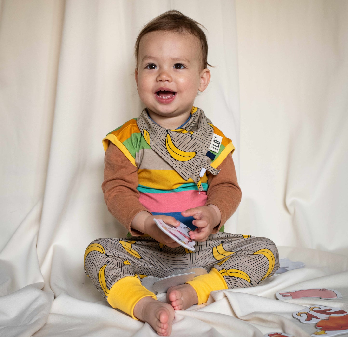Child wearing the bananas print bandana bib taggy dribble on mint colour organic cotton jersey